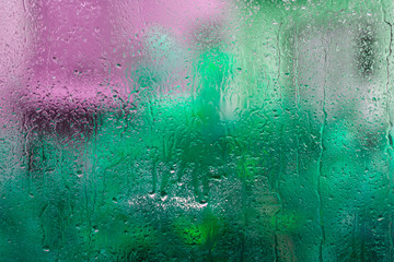 Wet glass with green pink blurs