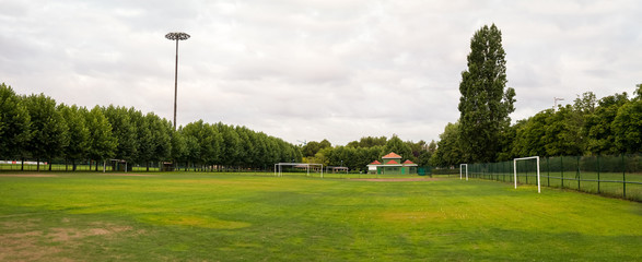 Panoramic view of sports facilities with football field for fans surrounded by trees and the changing rooms in the background in urban public park © Siur