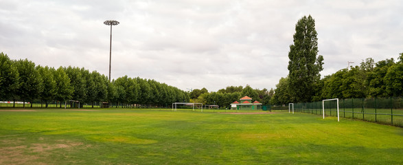 Panoramic view of sports facilities with football field for fans surrounded by trees and the...