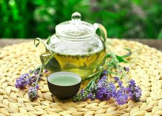 Lavender tea in a glass teapot on a table in the garden.
