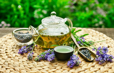 Lavender tea in a glass teapot on a table in the garden.