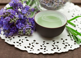 Obraz na płótnie Canvas Lavender tea in clay cup with lavender flowers on a wooden background.