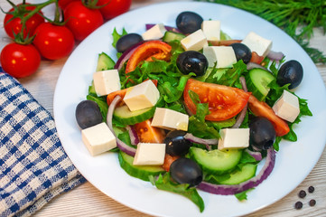 Greek salad with tomatoes, cucumbers and feta cheese with olives on the table