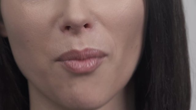 Close-up of beautiful female lips. Unrecognizable woman putting hazelnut into mouth.