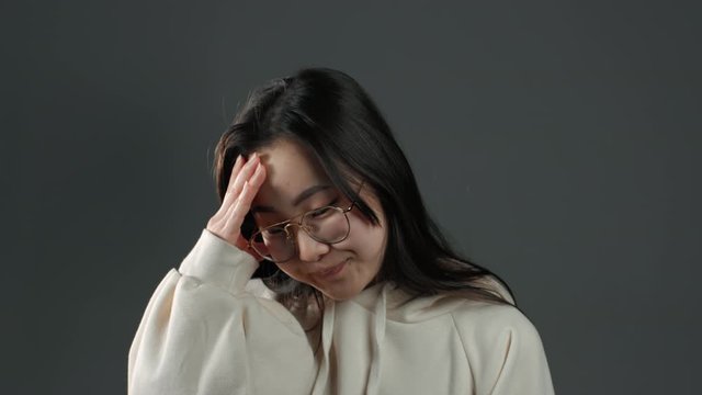 Portrait of young asian woman doing facepalm gesture, like no, I forgot. Unhappy korean woman with long hair feeling sorrow, regret, drama, failure.i She isolated on grey wall