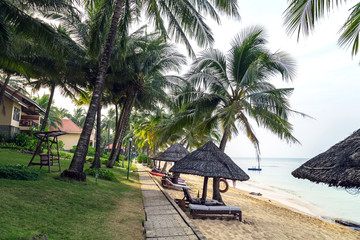 Long Beach, Phu Quoc Island, Vietnam. Nobody on the beach. Palm tree bamboo umbrellas and sun chairs in background.