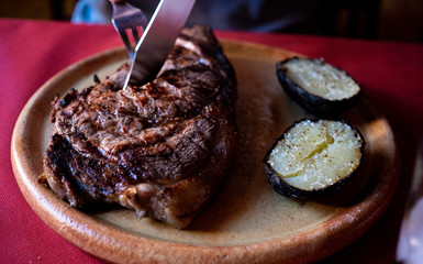 Hombre cortando un trozo de carne con cuchillo en unrestaurante