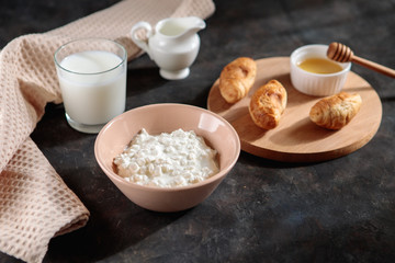 Cottage cheese with a glass of milk and croissants with honey on the table, space for text. Tasty breakfast.