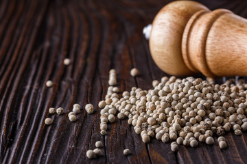 white peppercorns in wooden scoop on rustic background