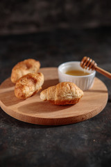 Croissants with honey on the table, close-up, on a dark background. Fresh bakery.