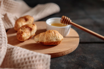 Croissants with honey on the table, close-up, on a dark background. Fresh bakery.