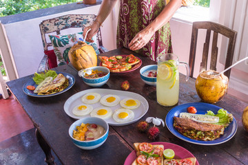 women's hands set the table with healthy food, healthy food, vegetables, fruits, lemonade, coconut on authentic table made of wood.