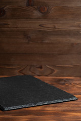Crockery slate, black stone on a wooden background.