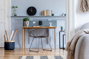 Scandinavian home office interior with wooden desk, design chair, wood panleing with shelf, plant,...