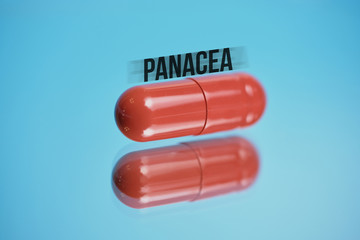 Red capsule with abstract inscription panacea on a blue background.