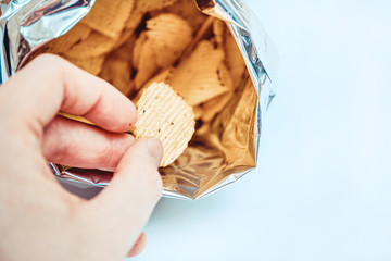 Fototapeta premium A hand takes out a foil packaging chips on a white background. Top view.