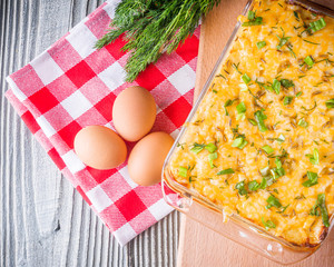 Delicious potato casserole with egg and cheese on a gray wooden background