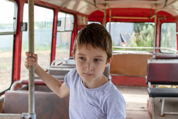 Obraz premium A 10 years boy riding in a old vintage bus, he is sad because his poor life and the bus moving going on a dirty country road