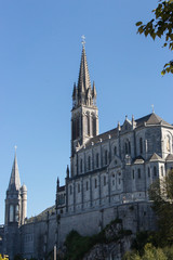 Fototapeta na wymiar Lourdes, France - 10/01/2019: Sanctuary of Our Lady of Lourdes on sunny day. Spiritual centre of pilgrims. Medieval religious architecture. Basilica in Lourdes. Famous catholic cathedral. 