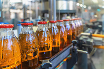 Conveyor belt, juice in bottles on beverage plant or factory interior, industrial production line,...