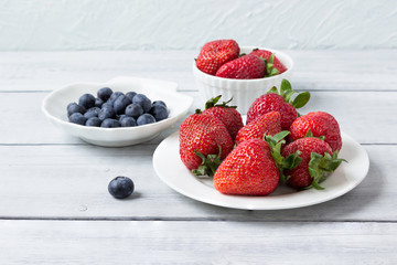 Fresh berries (strawberries and blueberries )  in plates on the table.