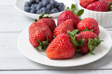Fresh berries (strawberries and blueberries )  in plates on the table.