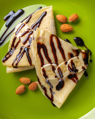 crepes with banana and chocolate spread on a green plate