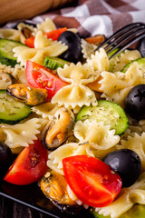 Delicious pasta salad with tomato cucumber and olives on wooden rustic background