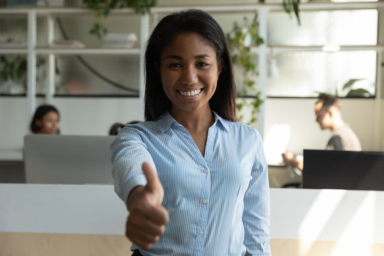 Portrait of smiling African American young female employee pose in modern office show thumbs up give recommendation, happy biracial millennial woman worker or client recommend good service - Powered by Adobe
