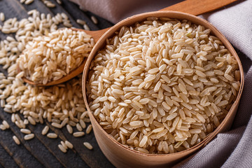 raw brown rice on dark rustic wooden background