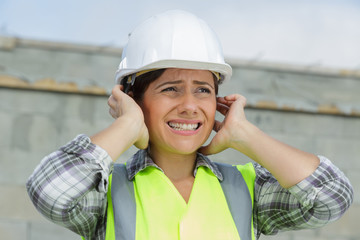 portrait of female constructor covering her ears