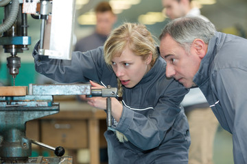 engineer training female apprentice on milling machine - obrazy, fototapety, plakaty