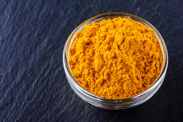 natural turmeric powder on a dark stone background