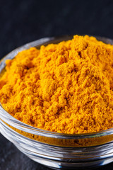 natural turmeric powder on a dark stone background