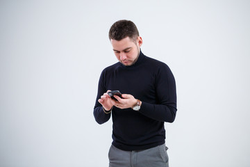 Serious guy businessman in black clothes finds out important questions by phone. Working day concept