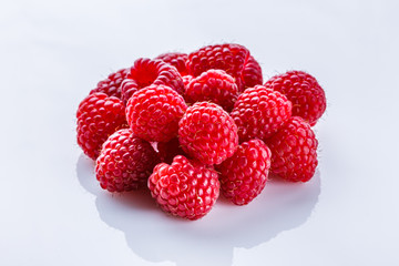 Juicy fresh natural raspberries on white acrylic background