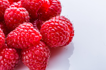 Juicy fresh natural raspberries on white acrylic background
