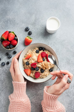 Female hands holding bowl of oatmeal porridge with berries. Concept of clean eating, dieting, healthy lifestyle. Copy space for text or design