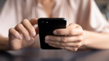 Close up front view young woman holding smartphone, typing message, chatting with friends in social networks. Female client using application on mobile phone, shopping online, web surfing, order food.