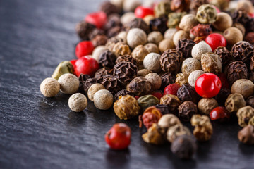 mix of peppercorns on a dark stone background