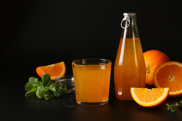 Orange tropical orange juice with basil seeds in bottle and glass on black background, Copy space