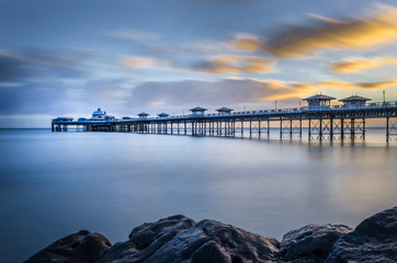 A morning shot of the Pier at Llandudno a coastal town in North Wales showing the calm water and floating clouds. 