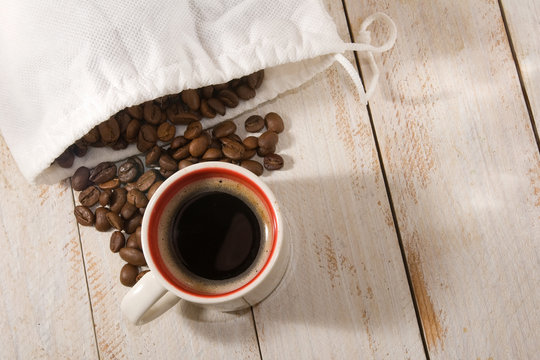 image of a cup with coffee and coffee beans on the table