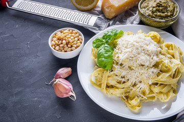 Delicious tagliatelle pasta with pesnto sauce on dark stone background