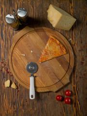 Slice of pizza, tomatoes, cheese, olive oil on a wooden table