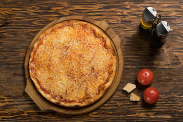 Pizza, tomatoes, cheese, olive oil on a wooden table