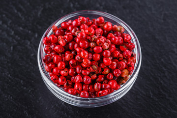 pink peppercorns on a dark stone background