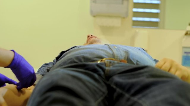nurse gives an intravenous injection to a man in a denim suit