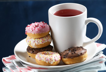  White tea cup with donuts on a white plate.