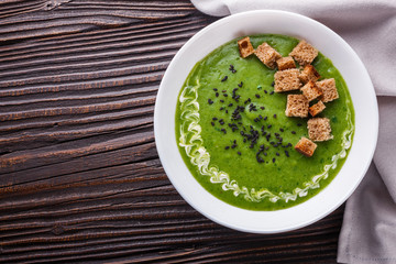 broccoli spinach cream soup on rustic wooden background